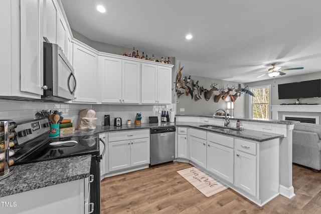 kitchen featuring sink, white cabinets, light hardwood / wood-style floors, kitchen peninsula, and stainless steel appliances