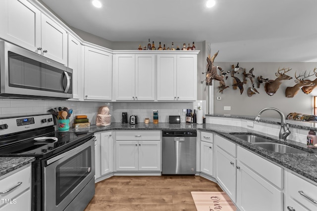 kitchen featuring dark stone countertops, appliances with stainless steel finishes, sink, and white cabinets