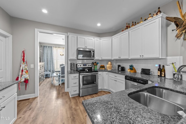 kitchen featuring sink, stainless steel appliances, dark stone counters, and white cabinets