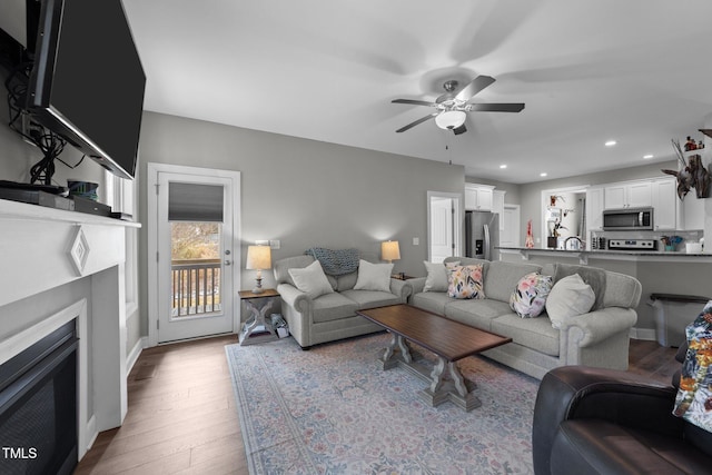 living room featuring ceiling fan, sink, and light hardwood / wood-style floors