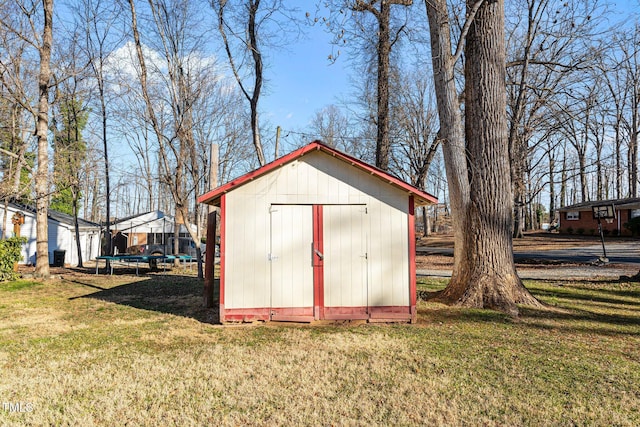 view of outbuilding featuring a trampoline and a lawn