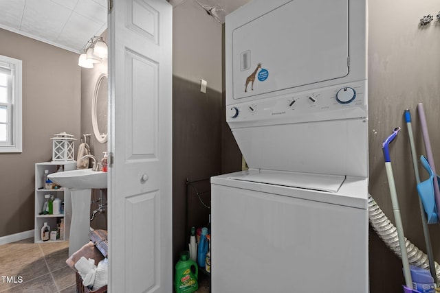 washroom with dark tile patterned floors and stacked washer / drying machine