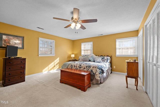 carpeted bedroom with ceiling fan and a textured ceiling