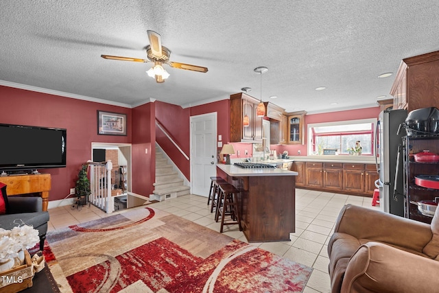 tiled living room featuring crown molding, ceiling fan, sink, and a textured ceiling