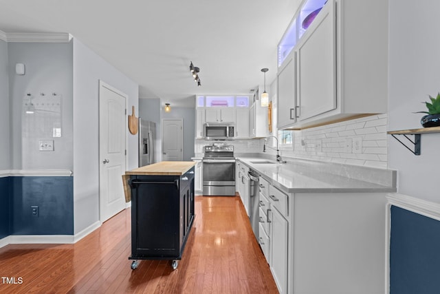 kitchen with sink, a center island, appliances with stainless steel finishes, pendant lighting, and white cabinets