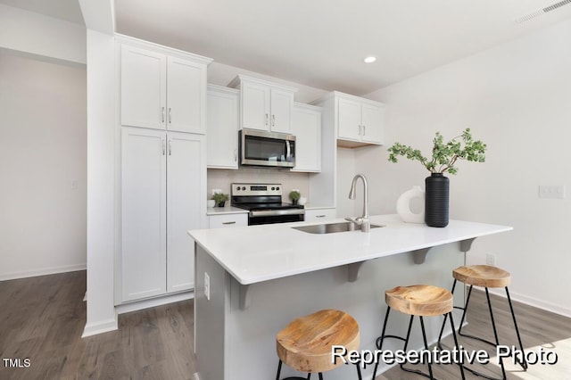 kitchen featuring a kitchen bar, sink, appliances with stainless steel finishes, and an island with sink