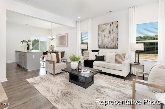 living room featuring sink, hardwood / wood-style flooring, and a notable chandelier