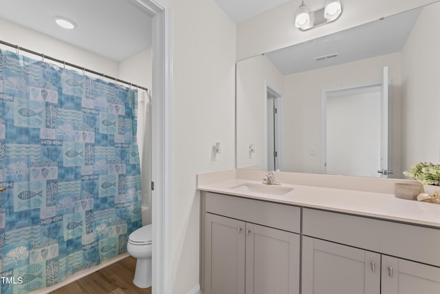 full bathroom with hardwood / wood-style flooring, shower / bathtub combination with curtain, vanity, and toilet