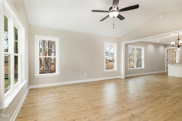 unfurnished room featuring ceiling fan with notable chandelier, vaulted ceiling, and light wood-type flooring