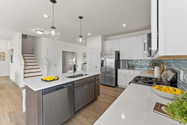 kitchen featuring sink, stainless steel appliances, white cabinetry, and a kitchen island with sink