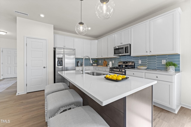 kitchen featuring sink, a breakfast bar area, a center island with sink, and appliances with stainless steel finishes