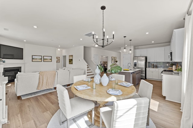 dining room with light hardwood / wood-style floors, sink, and a chandelier