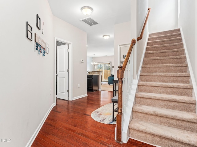 staircase with wood-type flooring and a chandelier