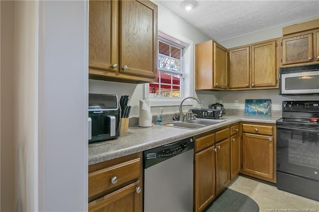 kitchen with sink, a textured ceiling, light tile patterned floors, and appliances with stainless steel finishes