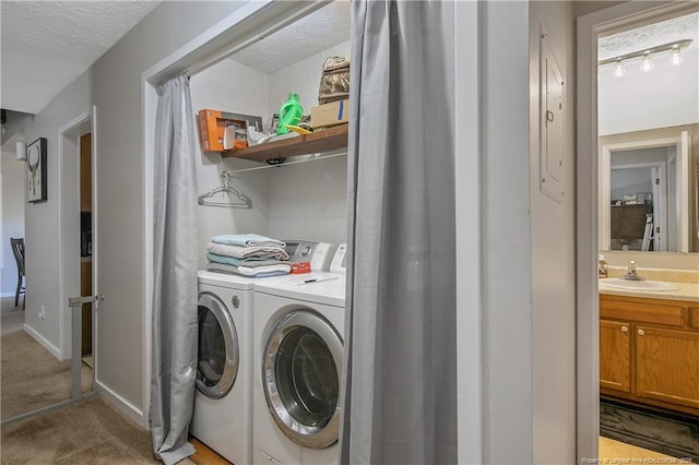 laundry room featuring sink, light carpet, washer and clothes dryer, and a textured ceiling