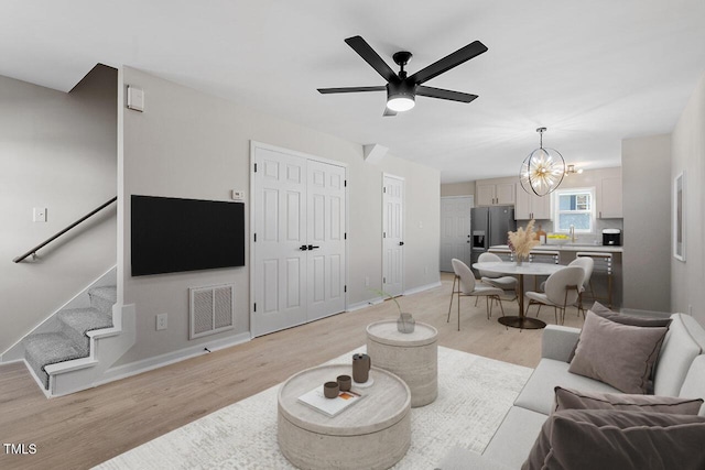 living room with light hardwood / wood-style floors, sink, and ceiling fan with notable chandelier