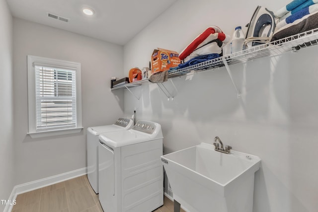 laundry area with visible vents, baseboards, washing machine and clothes dryer, laundry area, and a sink