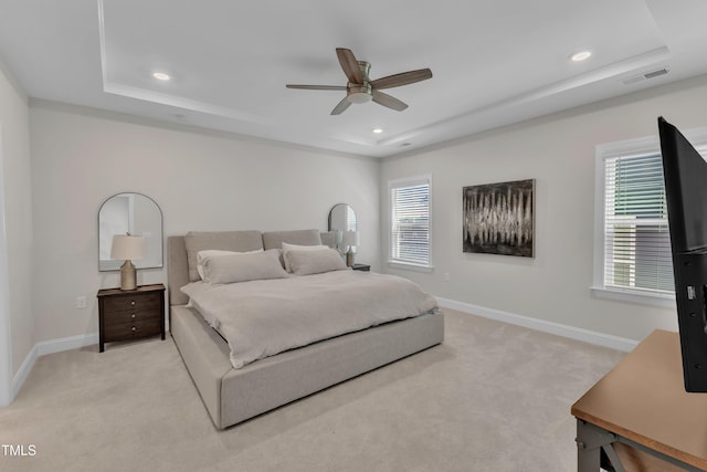 bedroom featuring light carpet, visible vents, a raised ceiling, and baseboards