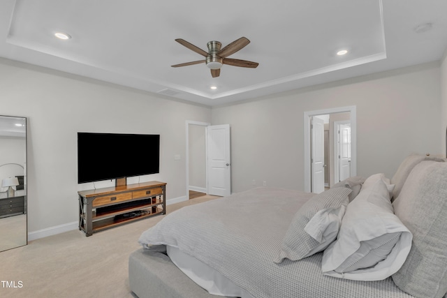 bedroom featuring recessed lighting, a tray ceiling, baseboards, and light colored carpet