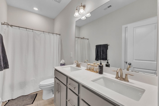 full bath with a sink, visible vents, toilet, and double vanity