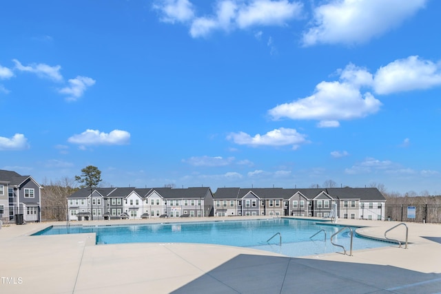 community pool featuring a patio area, a residential view, and fence