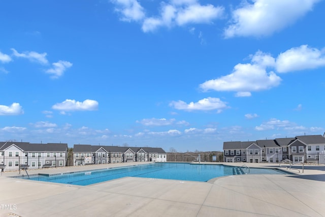 pool with a patio area, a residential view, and fence