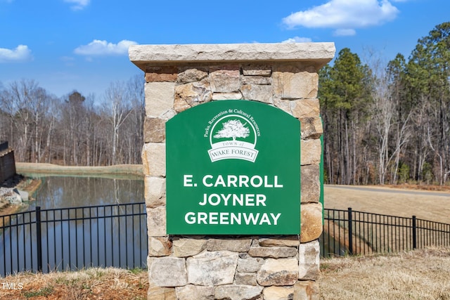 community / neighborhood sign with a water view and fence