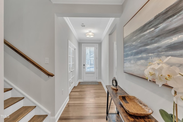 foyer with ornamental molding, stairs, baseboards, and wood finished floors