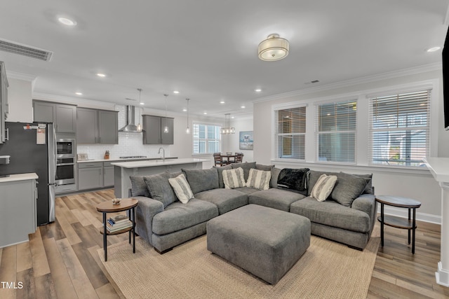 living room with crown molding, recessed lighting, visible vents, and light wood-type flooring