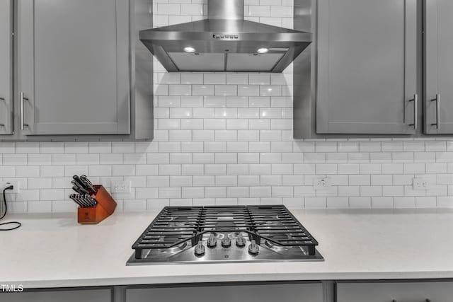 kitchen featuring gray cabinetry, wall chimney exhaust hood, and stainless steel gas cooktop