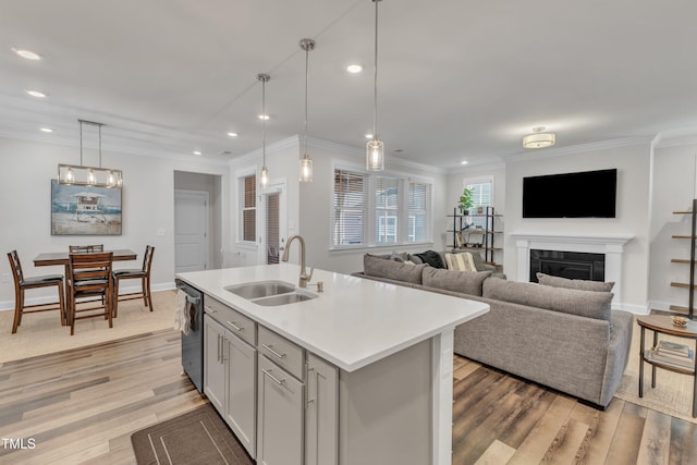 kitchen featuring light wood-style flooring, ornamental molding, a sink, light countertops, and dishwasher