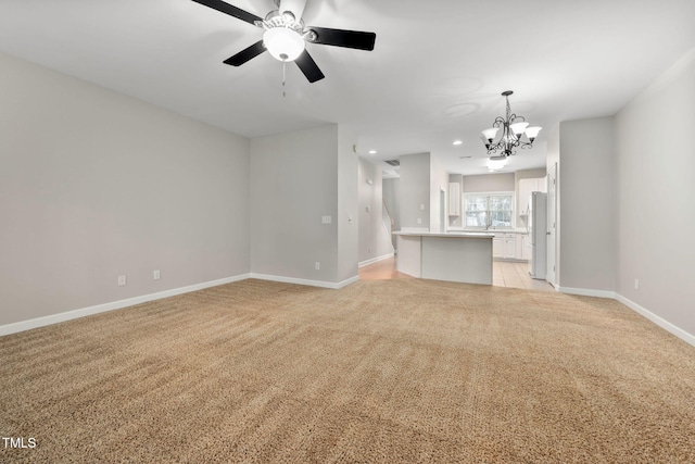 unfurnished living room with ceiling fan with notable chandelier and light colored carpet