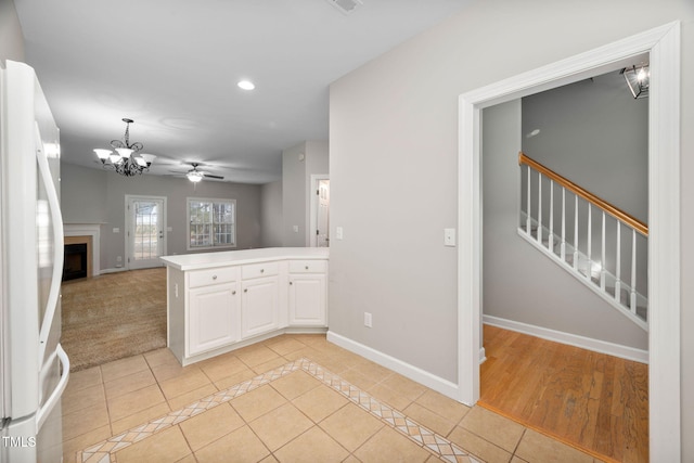 kitchen featuring white cabinetry, light tile patterned floors, kitchen peninsula, ceiling fan with notable chandelier, and white refrigerator