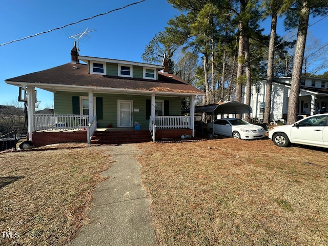 bungalow-style home with covered porch, a front yard, and a carport