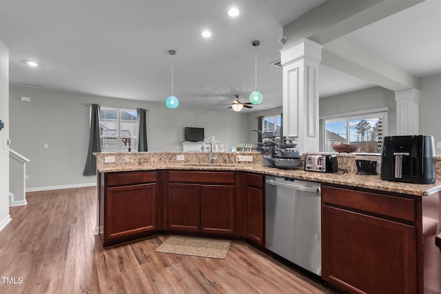 kitchen featuring ornate columns, hanging light fixtures, stainless steel dishwasher, sink, and light wood-type flooring