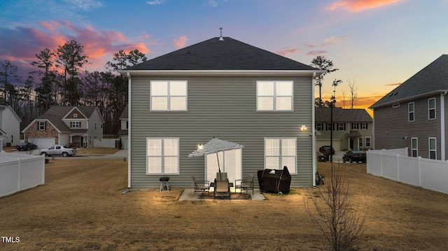 back house at dusk featuring a yard and a patio