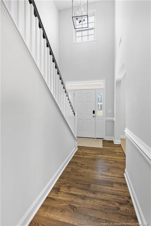 foyer with a chandelier, a towering ceiling, a wealth of natural light, and dark hardwood / wood-style flooring