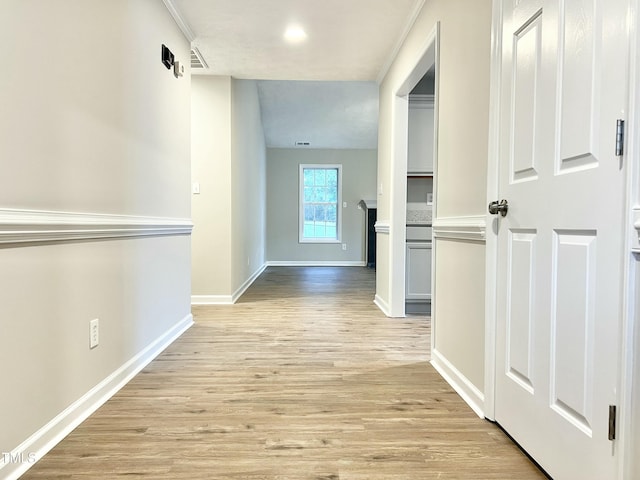 corridor with light wood-type flooring and crown molding