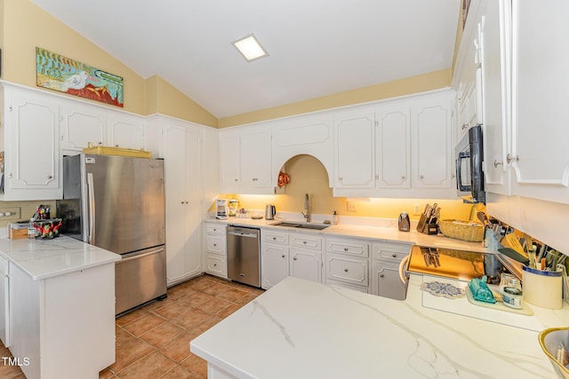 kitchen featuring a sink, a peninsula, white cabinetry, vaulted ceiling, and stainless steel appliances