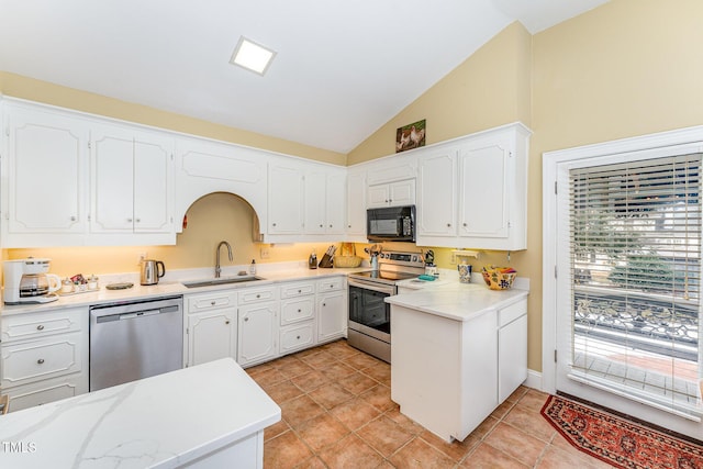 kitchen featuring white cabinets, a sink, light countertops, appliances with stainless steel finishes, and lofted ceiling