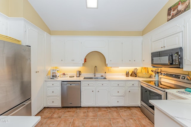 kitchen featuring vaulted ceiling, a sink, white cabinetry, and appliances with stainless steel finishes