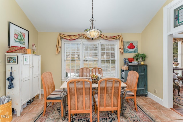 dining area with light tile patterned floors, baseboards, and vaulted ceiling