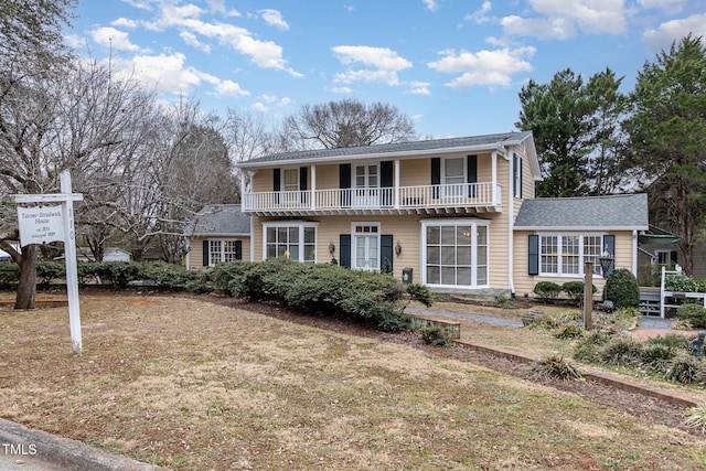 front of property featuring a front lawn and a balcony