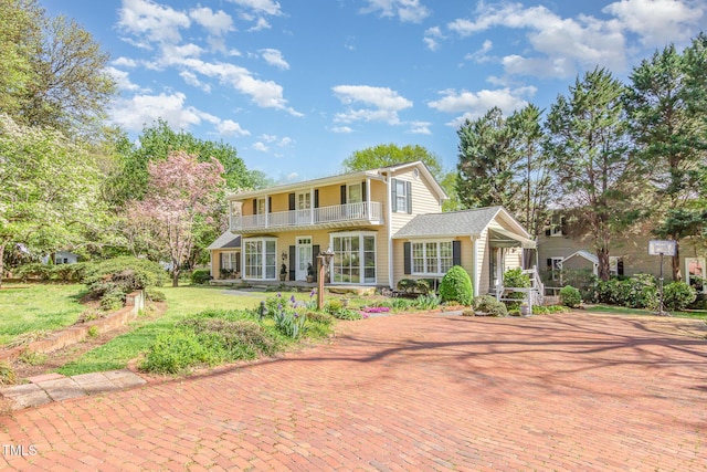 view of front of house with a front lawn and a balcony