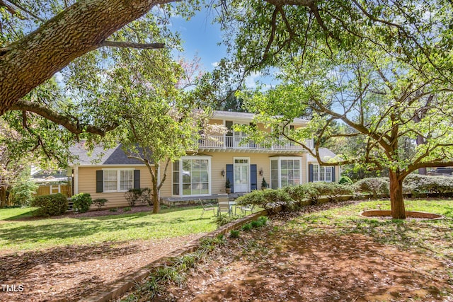 view of front of house featuring a front lawn and a balcony