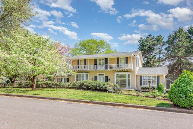 view of front of home featuring a balcony and a front lawn