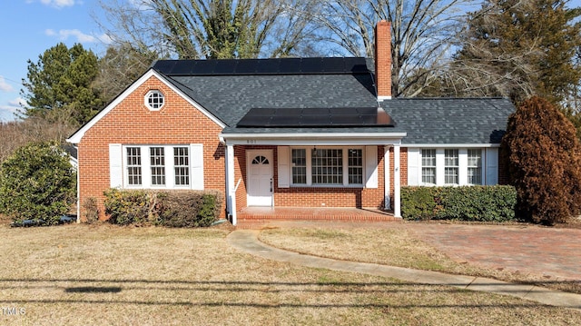 view of front of home with a front lawn, covered porch, and solar panels