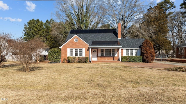 view of front of property featuring a front lawn, solar panels, and a porch