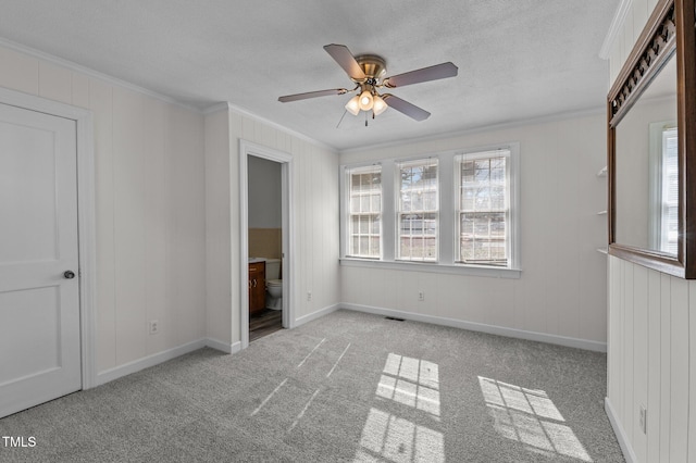 unfurnished bedroom featuring crown molding, ensuite bath, light carpet, and ceiling fan