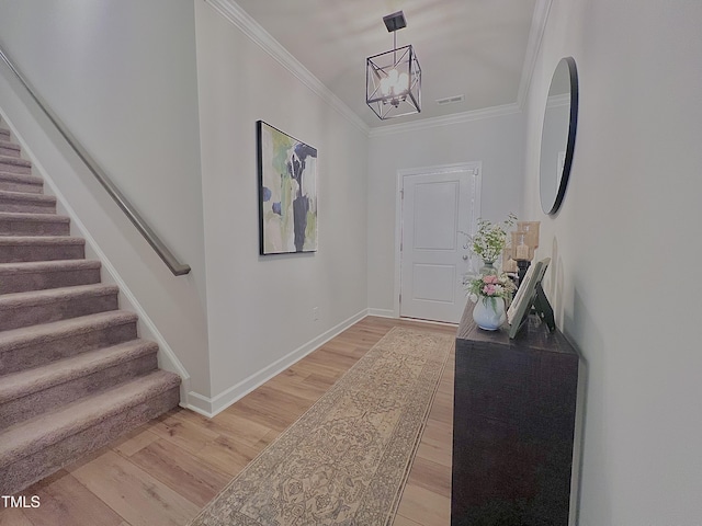 foyer entrance featuring a notable chandelier, hardwood / wood-style flooring, and crown molding